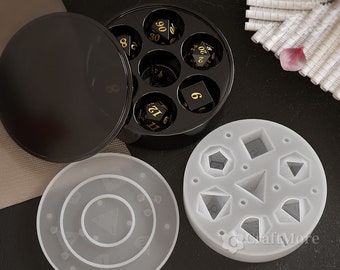 May include: A set of six black dice with gold numbers in a black circular container with a lid.  There are also two white silicone molds for making dice.