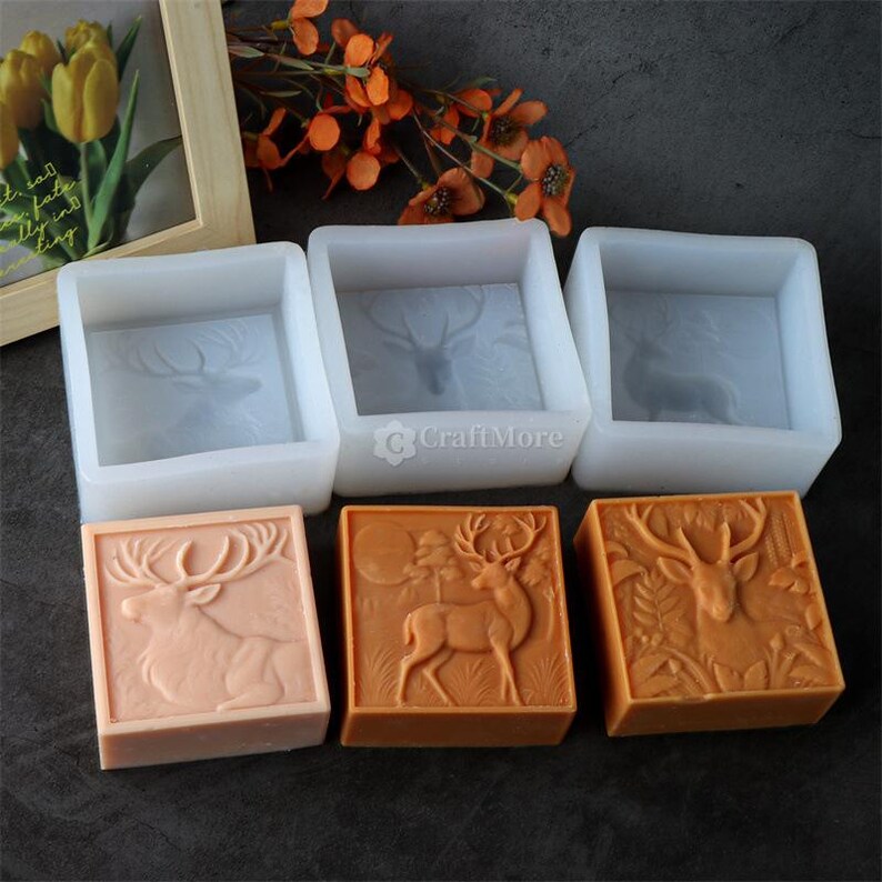 Pode incluir: Uma cole&ccedil;&atilde;o de moldes quadrados de silicone e sabonetes acabados. Os moldes s&atilde;o brancos e apresentam um design de veado. Os sabonetes s&atilde;o p&ecirc;ssego e laranja, tamb&eacute;m com desenhos de veados. Os sabonetes s&atilde;o quadrados e t&ecirc;m relevo.