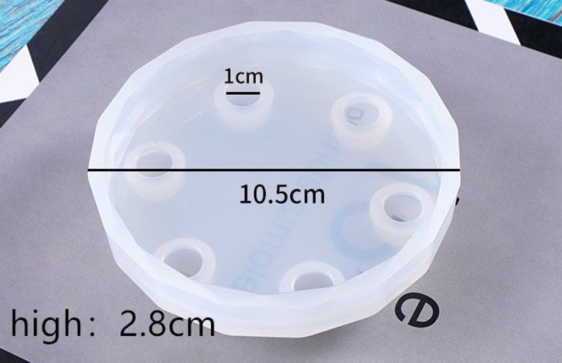 May include: A clear silicone mold with six round indentations for making resin crafts. The mold is 10.5 cm in diameter and 2.8 cm high. The indentations are 1 cm in diameter.