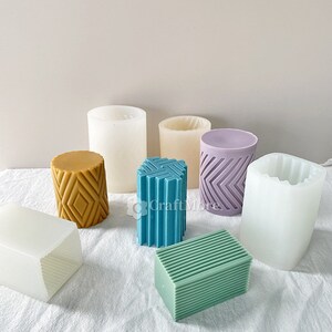 May include: Assortment of silicone candle moulds in various shapes and sizes. The moulds are white, purple, blue and yellow with geometric patterns.