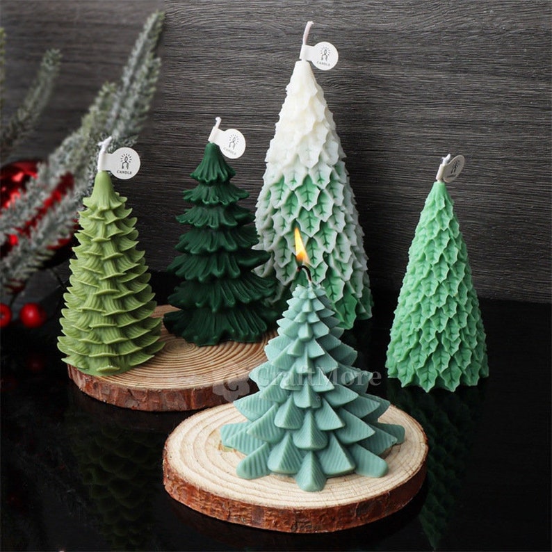 May include: Five green and white Christmas tree candles on wooden bases. The candles are decorated with a leaf pattern and have a white label with the word "Candle" on them.