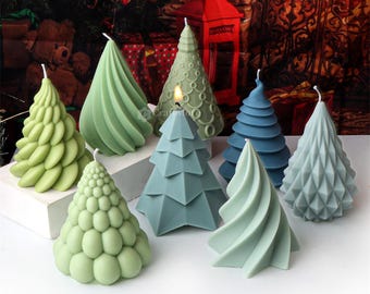May include: Assortment of green and blue Christmas tree shaped candles. The candles are made in various styles, including a swirl, a geometric design, and a textured design.