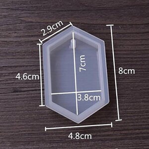 May include: A clear silicone mold shaped like a hexagon with rounded edges. The mold is 7 cm tall, 4.8 cm wide, and 4.6 cm long. It has a 3.8 cm wide opening at the top.