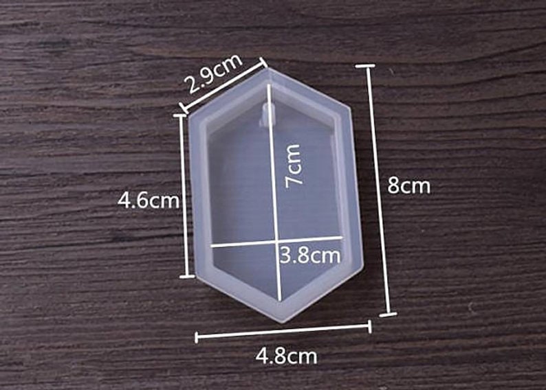 May include: A clear silicone mold shaped like a hexagon with rounded edges. The mold is 7 cm tall, 4.8 cm wide, and 4.6 cm long. It has a 3.8 cm wide opening at the top.