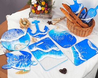 May include: A set of nine resin serving trays with ocean wave designs. The trays are in various shapes, including a turtle, an anchor, and a rectangle. The trays are all blue and white with white waves on a blue background.