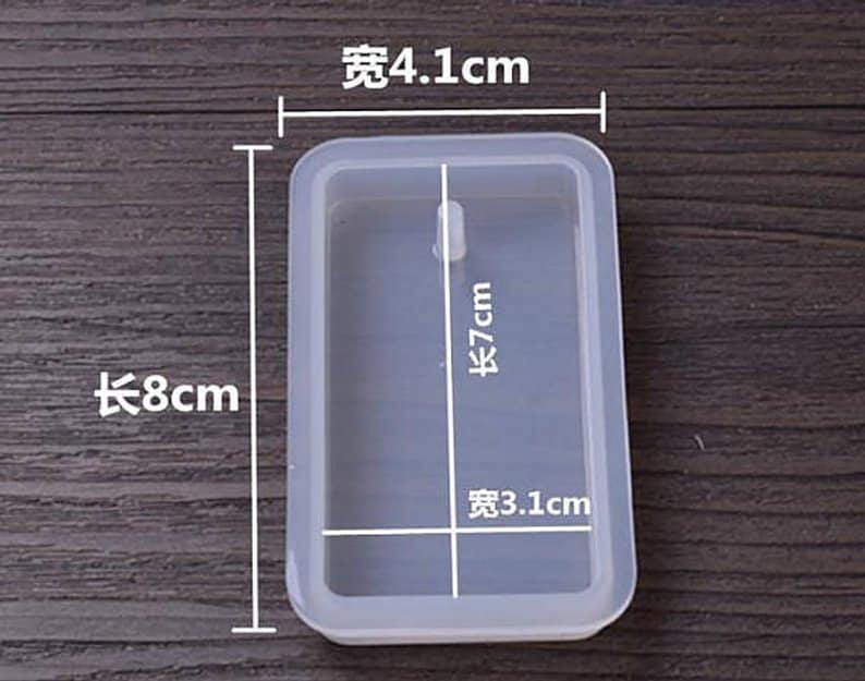 May include: A clear rectangular silicone mold with measurements in centimeters. The mold is 8 cm long, 7 cm tall, and 4.1 cm wide. The mold is designed to create a rectangular shape with a small hole in the center.