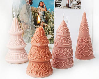 May include: Four decorative Christmas tree candles in pink and brown with intricate designs. The candles are arranged on a white surface.
