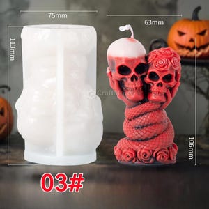 Op de afbeelding: Een siliconen mal voor het maken van een kaars in de vorm van twee rode schedels die met een slang en rozen in elkaar zijn verweven. De mal is 19 cm hoog en 11,5 cm breed. De afgewerkte kaars is 10,5 cm hoog en 6,5 cm breed.