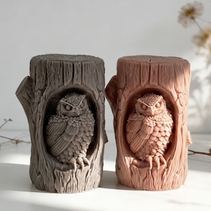 Może przedstawiać: Dwie rzeźby sów wyrzeźbione w pniach drzew. Jedna jest ciemnoszara, druga jasnobrązowa. Sowy mają szczegółowe wzory piór i są umieszczone wewnątrz pni.