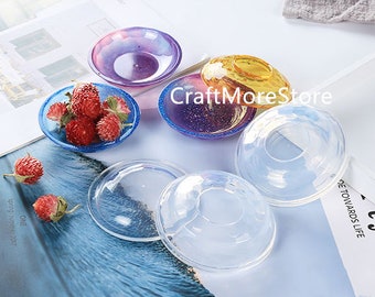 May include: Assortment of clear resin molds for crafting. The molds are round and have a raised center. There are also several smaller, colorful resin molds in the image.