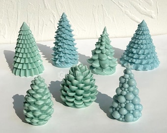 May include: Seven different teal blue and green Christmas tree-shaped candles. The candles are made of wax and have a variety of designs, including a pine cone, a tree with ornaments, and a traditional Christmas tree.