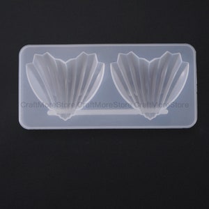 May include: A clear silicone mold with two shell-shaped cavities. The mold is designed for creating resin crafts.