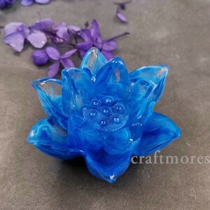 May include: A blue resin lotus flower with white swirls. The flower has a detailed center with a series of small circles.