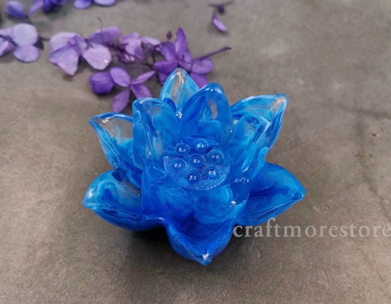 May include: A blue resin lotus flower with white swirls. The flower has a detailed center with a series of small circles.