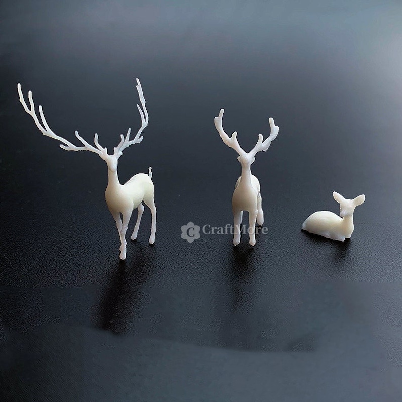 Pu&ograve; includere: Tre figurine di cervi bianche, una in piedi con grandi corna, una in piedi con corna pi&ugrave; piccole e una sdraiata. I cervi sono fatti di un materiale bianco liscio.