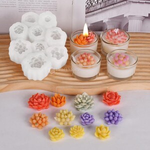 May include: A set of silicone molds for making succulent shaped candles. The molds are white and have a detailed design. There are also several finished candles in various colors, including green, pink, orange, and yellow.