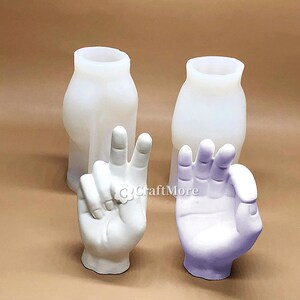 May include: Two white silicone molds for making hand-shaped objects. One mold is shaped like a hand making a peace sign, the other is shaped like a hand making an okay sign.