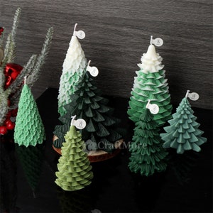 May include: Five green and white Christmas tree candles with a textured leaf design. The candles are arranged on a wooden surface.