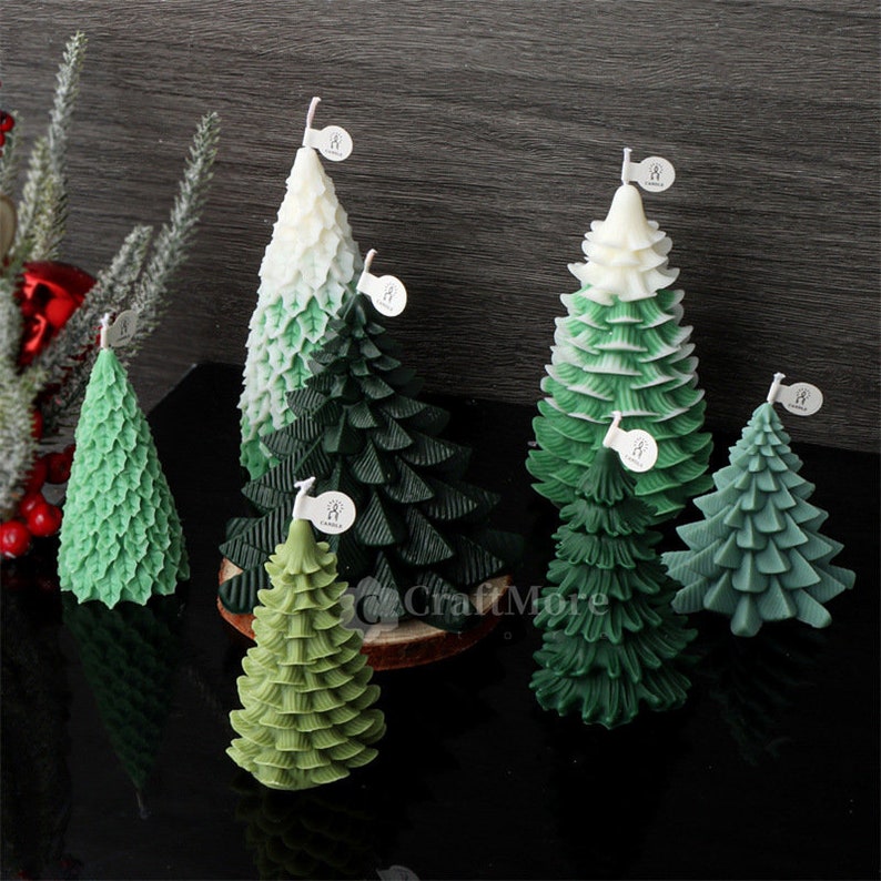 May include: Five green and white Christmas tree candles with a textured leaf design. The candles are arranged on a wooden surface.