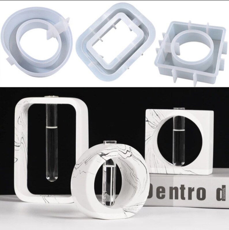 May include: Three white concrete vase molds with a marble pattern. The molds are in the shape of a square, a circle, and a rectangle. Each mold has a circular opening for a test tube.