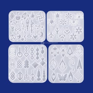 May include: Four clear silicone molds with various earring designs. The molds feature a variety of shapes, including leaves, flowers, geometric shapes, and abstract designs. The molds are arranged on a dark blue background.