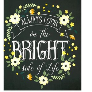 May include: A dark charcoal rectangular sign featuring the white text "ALWAYS LOOK on the BRIGHT side of Life" centered within a decorative wreath of yellow flowers, orange buds, and green leaves arranged in a circular pattern around the lettering.