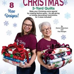 May include: A quilt pattern book titled Quick Christmas 3-Yard Quilts by Fabric Café, featuring 8 new designs. The cover displays text about creating festive quilts in 3 sizes, with illustrations of snowflakes and two stacks of folded quilts.