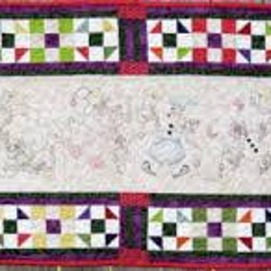 May include: A white fabric wall hanging with a colorful patchwork border. The center of the wall hanging features a white embroidered design of a group of figures wearing hats and holding objects.