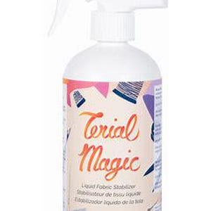 May include: A white plastic bottle with a spray nozzle, labeled "Terial Magic." The label features colorful geometric shapes and text, including "Liquid Fabric Stabilizer" and "10 fl oz."