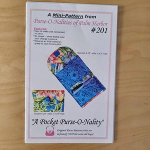 May include: A sewing pattern booklet titled A Mini-Pattern from Purse-O-Nalities of Palm Harbor #201. It displays a floral and blue patterned fabric pocket purse, showing an open view at 4.25 inches wide by 8.5 inches high and closed at 4.25 inches wide by 3.25 inches high.