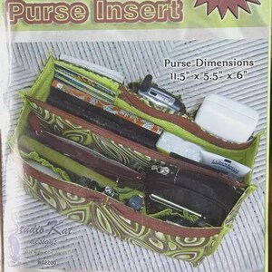 May include: The Encore Purse Insert is a green and brown patterned organizer with multiple compartments. It features printed text including 'The Encore Purse Insert', 'NEW Extra-LARGE Size!', and 'Purse Dimensions 11.5" x 5.5" x 6"'.