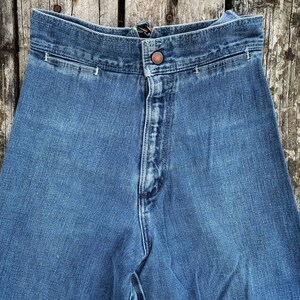 May include: A pair of blue denim jeans with a high waist and a button fly. The jeans have a classic straight leg style and are made of a durable denim fabric.