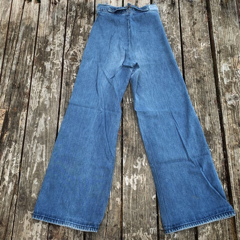 May include: A pair of wide-legged denim jeans with a high waist and a tie at the front. The jeans are a light blue wash and have a relaxed fit.
