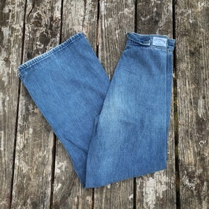 May include: A pair of blue denim wide-leg jeans with a Wrangler label on the back waistband.