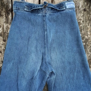 May include: A pair of blue denim jeans with a tie at the waist and a Wrangler label on the back pocket.