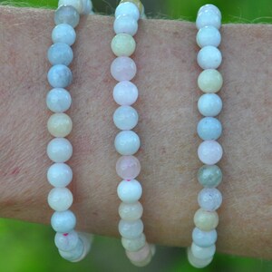 Peut inclure: Trois bracelets en perles de différentes nuances de bleu, rose et jaune. Les bracelets sont faits de perles rondes et lisses et sont empilés sur le poignet d'une personne.