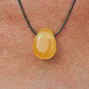 Peut inclure: Un pendentif en forme de larme de pierre précieuse jaune sur un collier en cordon de cuir noir.