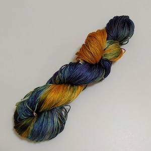 Könnte beinhalten: Eine Garnrolle in den Farben Blau, Grün und Orange. Das Garn ist verdreht und verknotet und zeigt die verschiedenen Farben.