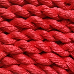 May include: Close-up of a red embroidery floss, showing the twisted strands of the thread.