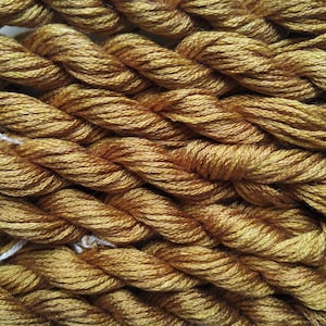May include: Close-up of a bundle of golden brown embroidery floss.