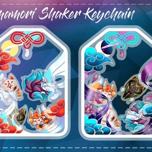 May include: A colorful keychain with a shaker charm featuring a Japanese Omamori design. The charm has a blue, white, and red color scheme with a white fox and a blue fox. The keychain is labeled "Chromantic Omamori Shaker Keychain".