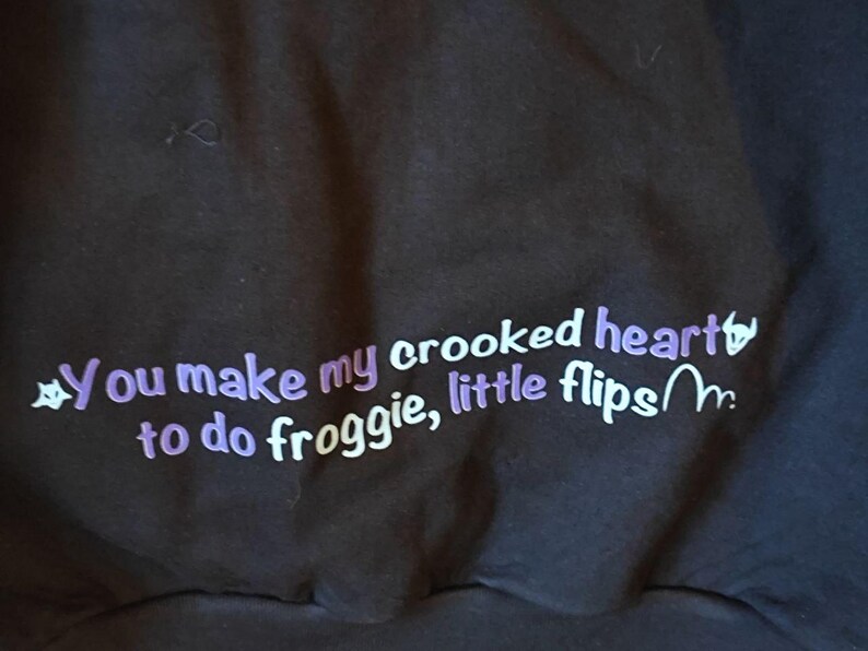 May include: A black sweatshirt with purple text that reads "You make my crooked heart to do froggy, little flips~m."