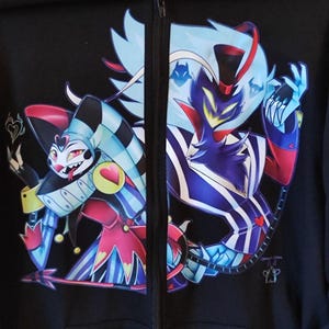 May include: Black zip-up hoodie with a colorful graphic print of two cartoon characters. The characters are a blue and red jester and a black and blue demon with a top hat. The hoodie has a purple hood.