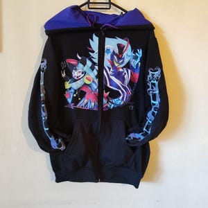 May include: Black zip-up hoodie with a colorful graphic print of two characters. The hoodie has a purple hood lining and blue and purple designs on the sleeves.