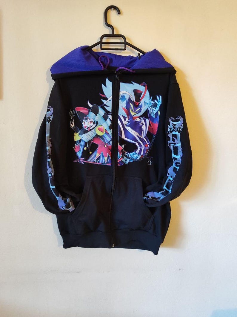 May include: Black zip-up hoodie with a colorful graphic print of two characters. The hoodie has a purple hood lining and blue and purple designs on the sleeves.