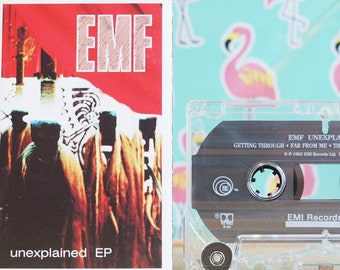 May include: A cassette tape with a clear plastic case and a black label. The label has the text "EMF UNEXPLAINED EP" and the song titles "GETTING THROUGH", "FAR FROM ME", "THE SAME", and "SEARCH AND DESTROY". The label also has the text "EMI Records Group" and the number "1".