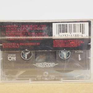 May include: Black cassette tape with a white label. The label has the band name "Poison" in white letters with a black background. The cassette tape has a barcode and the text "0 76732-6188-4 4". The text "Produced & Engineered by Tom Scholz" is also on the label.