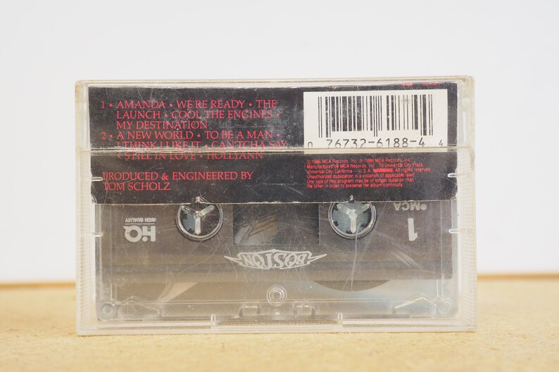 May include: Black cassette tape with a white label. The label has the band name "Poison" in white letters with a black background. The cassette tape has a barcode and the text "0 76732-6188-4 4". The text "Produced & Engineered by Tom Scholz" is also on the label.
