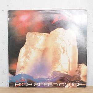 May include: A vintage vinyl record album cover featuring a large block of ice with a glowing light inside. The album cover is for the band "T" and the album title is "Live High Speed On Ice".
