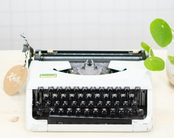 May include: A white vintage typewriter with a black keyboard and a green label that says "Olivetti"